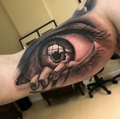 a man's arm with an eye tattoo on it and his hand holding the eye