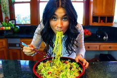 a woman eating noodles from a red bowl