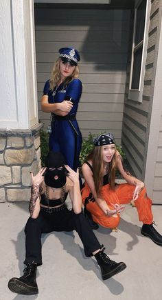 three people dressed in costumes sitting on the front steps of a house, one holding up her hand