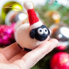 a hand holding a small stuffed animal with a santa hat on it's head