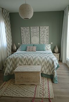 a bedroom with a bed, rugs and two lamps hanging from the ceiling above it