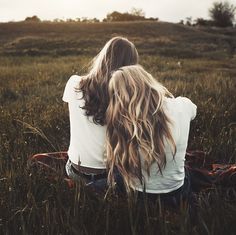 a woman sitting in the grass with her back turned to the camera