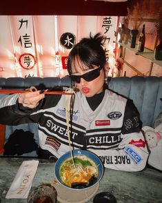 a woman eating noodles from a bowl with chopsticks