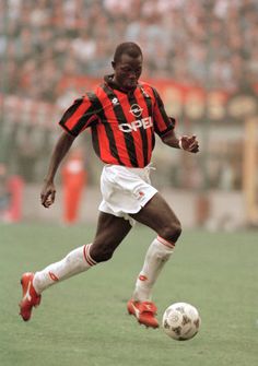 a man kicking a soccer ball on top of a field