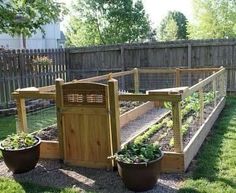 an outdoor vegetable garden with wooden fences and potted plants