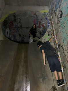 two skateboarders are riding down the side of a wall with graffiti on it