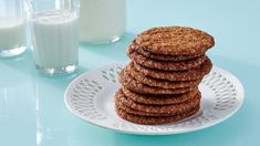 a stack of cookies sitting on top of a white plate next to a glass of milk