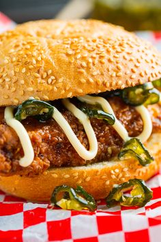 a close up of a sandwich with meat and peppers on a checkered table cloth