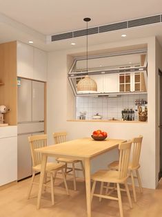 a table and chairs in a room with white walls, wood flooring and cabinets