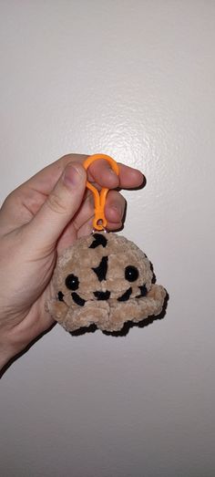 a hand holding a small stuffed animal with scissors in it's mouth and the other hand