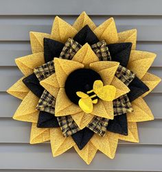 a yellow and black sunflower on the side of a house with a bee decoration