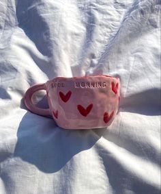 a pink cup with red hearts on it sitting on a white sheet that says god loving