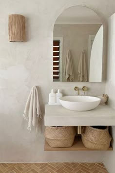 a bathroom with a sink, mirror and two baskets on the counter in front of it