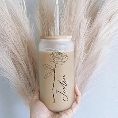 a person holding a drink in front of some dry grass with the word love written on it