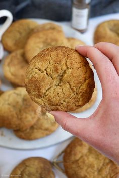 a person is holding a cookie in front of some muffins on a plate