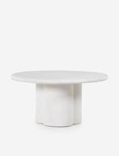 a white table with a round top on a grey background, it is made from marble