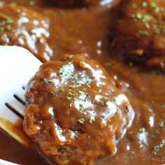 meatballs covered in gravy on a spoon