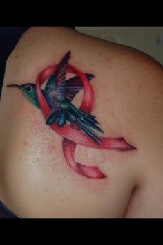 a woman with a tattoo on her back has a humming bird and ribbon around it