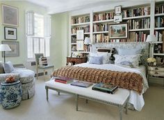 a bed sitting in a bedroom next to a chair and book shelf filled with books