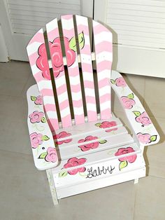 a pink and white striped wooden chair with flowers on the seat, sitting in front of a door