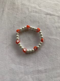 an orange and white beaded bracelet with silver beads on a white sheeted surface