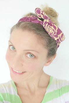 a woman with a flower in her hair wearing a purple and green striped shirt, smiling at the camera