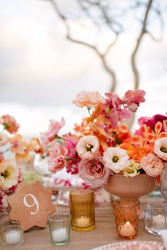 an arrangement of flowers and candles on a table