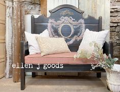 a wooden bench with pillows on it in front of a brick wall and potted plant