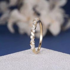 a gold wedding ring with five stones on it, sitting on a white cloth next to some flowers