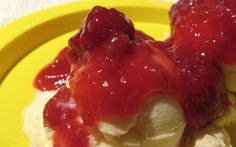 two scoops of ice cream and strawberry sauce on a yellow plate with white cloth