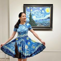 a woman in a blue dress standing next to a painting