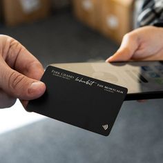 a person holding a black card in their hand with a cell phone next to it