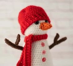 a crocheted snowman wearing a red hat and scarf