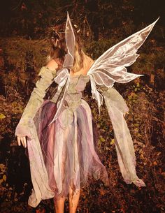 a woman dressed as a fairy standing in the woods