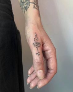 a person's hand with a tattoo on it, holding the finger of another person