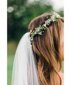 a woman wearing a veil and flowers in her hair is looking into the distance while she wears