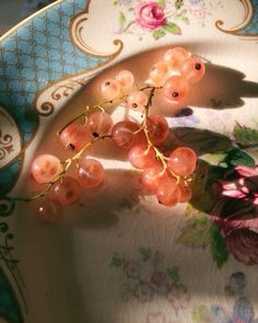 a bunch of grapes sitting on top of a white and blue plate with pink flowers