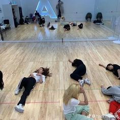 group of people laying on the floor in an indoor gym doing stretching exercises with each other