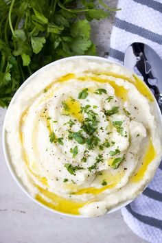 a white bowl filled with mashed potatoes and parsley on top of a striped towel