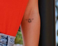 a woman's arm with a small tattoo of a bee on the back of her arm