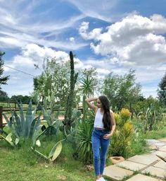 a woman standing in front of a cactus garden with her hand on her head and looking off into the distance