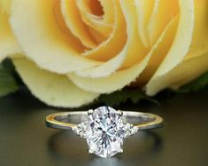 a close up of a ring on a table next to a flower and a rose