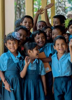 a group of young children standing next to each other in front of a building with their hands up