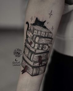 a black cat sitting on top of a stack of books