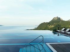 an empty swimming pool overlooking the ocean and mountains