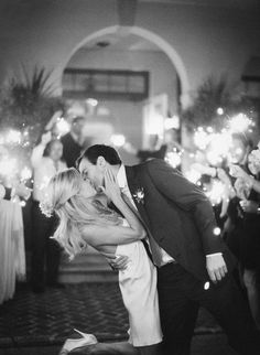 a couple kissing each other in front of a cake with candles and flowers on it