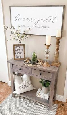 a wooden table with two white pillows and some plants on it next to a sign that says be gorgeous come in and stay awhile