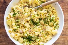 a white bowl filled with pasta on top of a wooden table