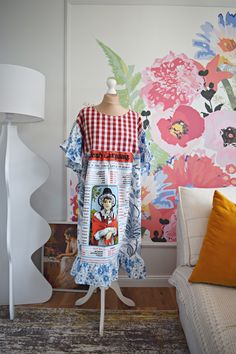 a dress on a mannequin in front of a colorful wallpapered room