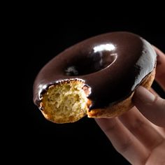 a hand holding a half eaten chocolate covered doughnut